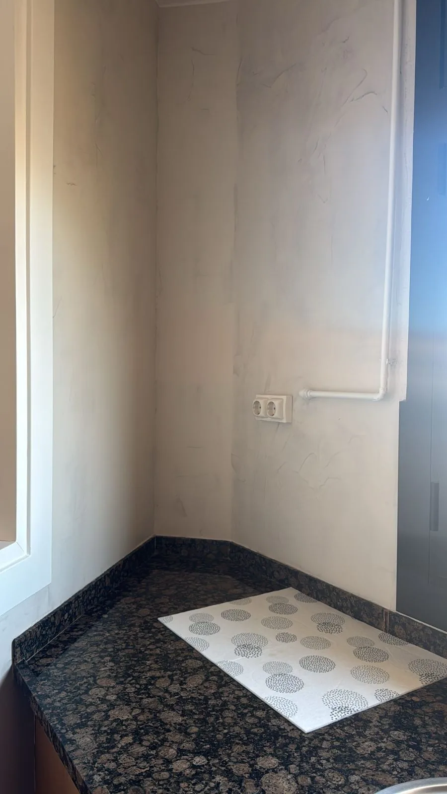 Esquina de cocina con paredes de microcemento y encimera de granito