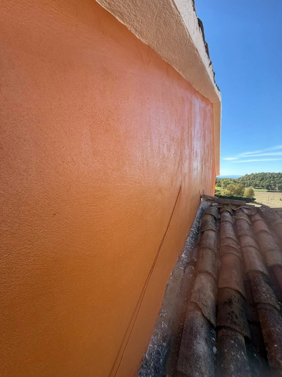 Pared exterior pintada en naranja junto a un tejado de teja